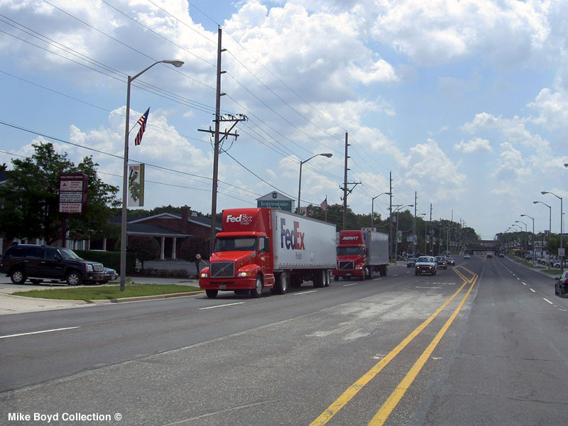 A FedEx Freight Volvo VN with a van on IL SR50 in IL. Aug. 2007.